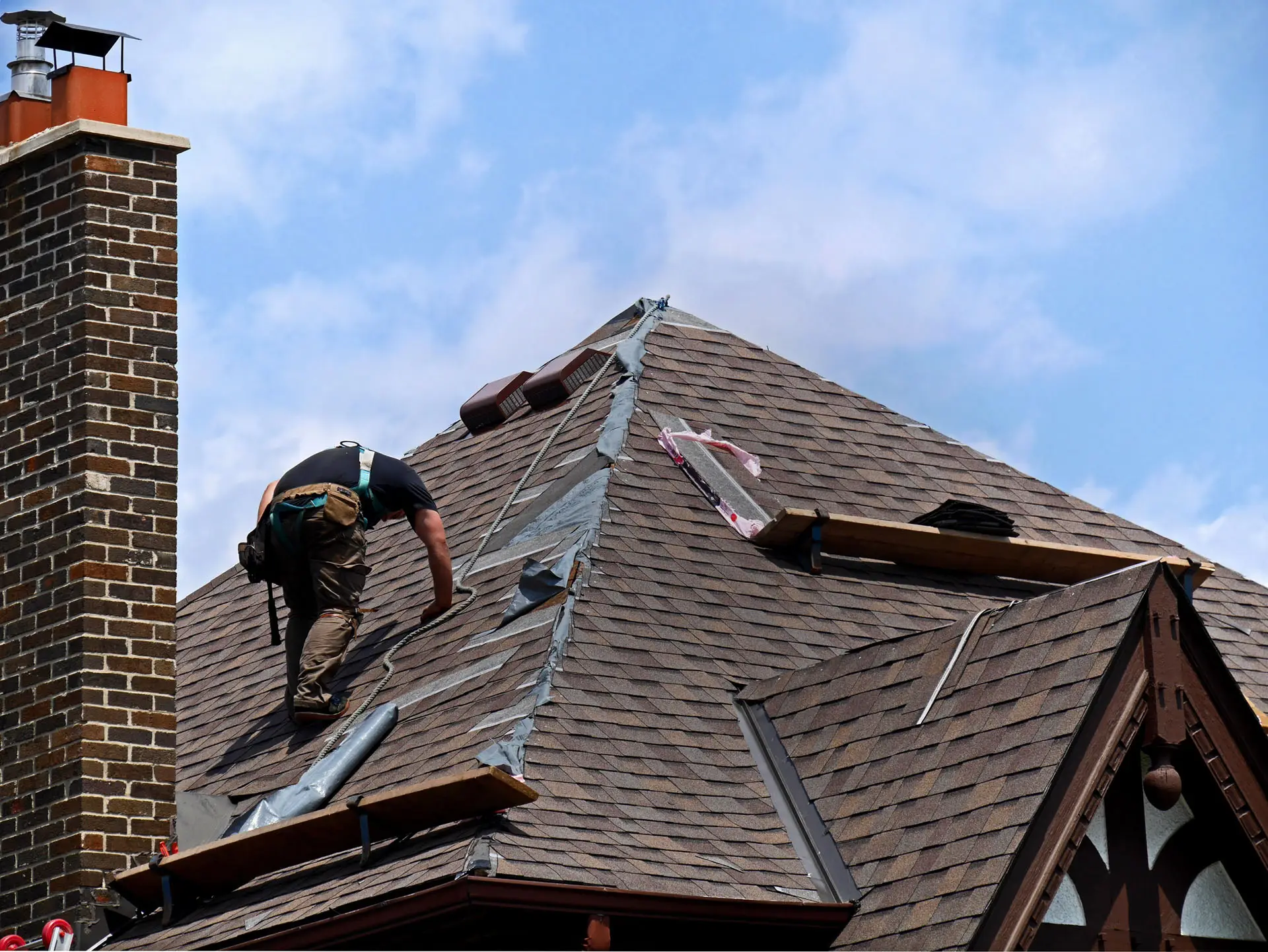 Roofer installing shingles on steep slope roof.