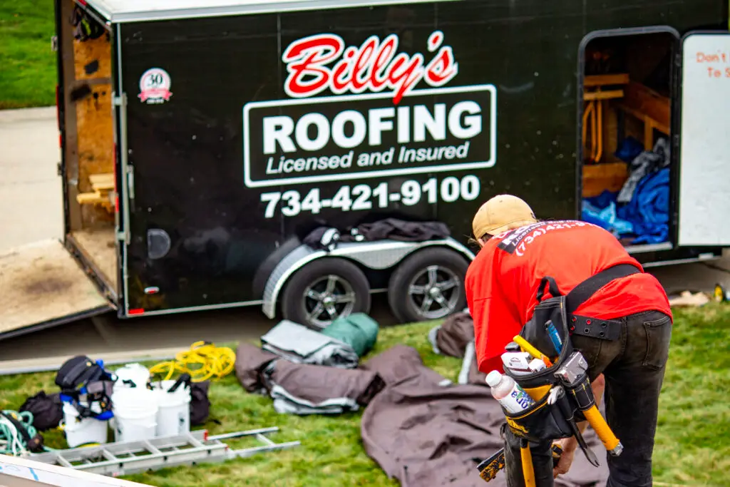 Billy's Roofing trailer and crew member at residential roof replacement in Metro Detroit.