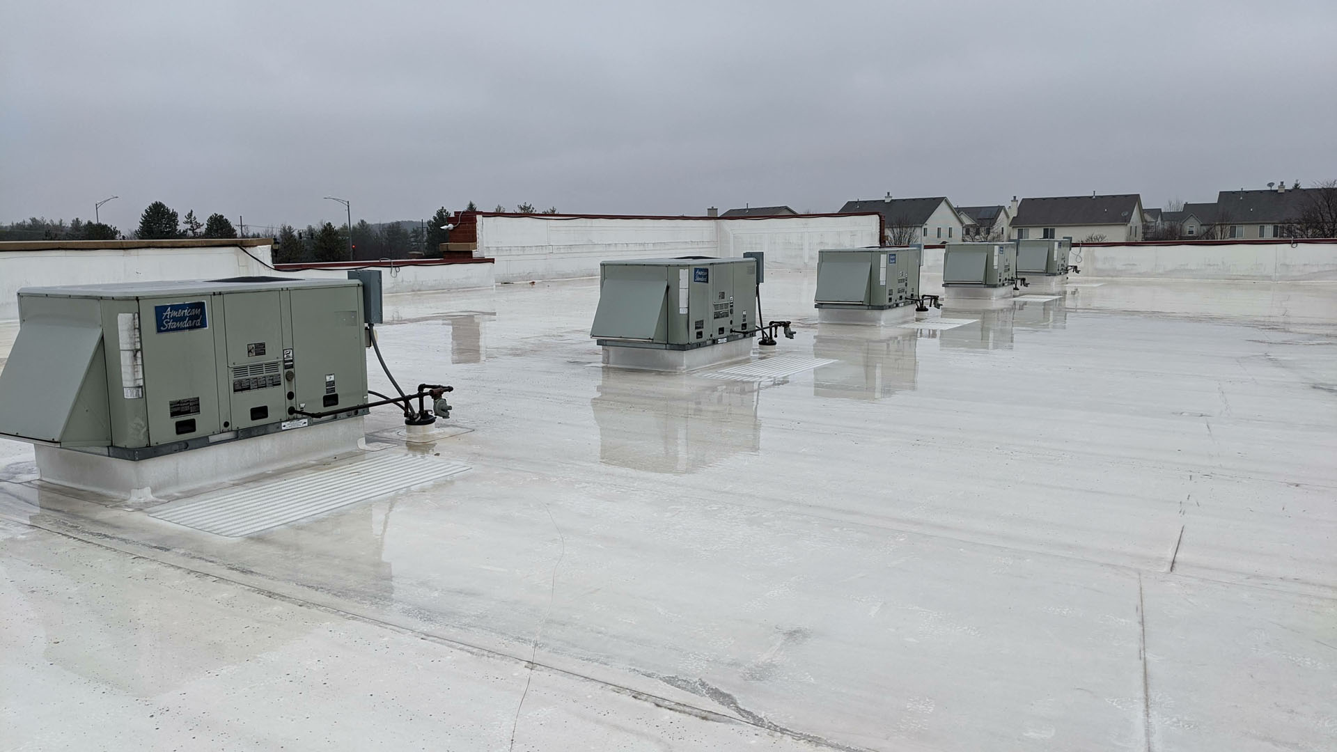 Commercial flat roof membrane roofing system with rooftop HVAC units and drainage features