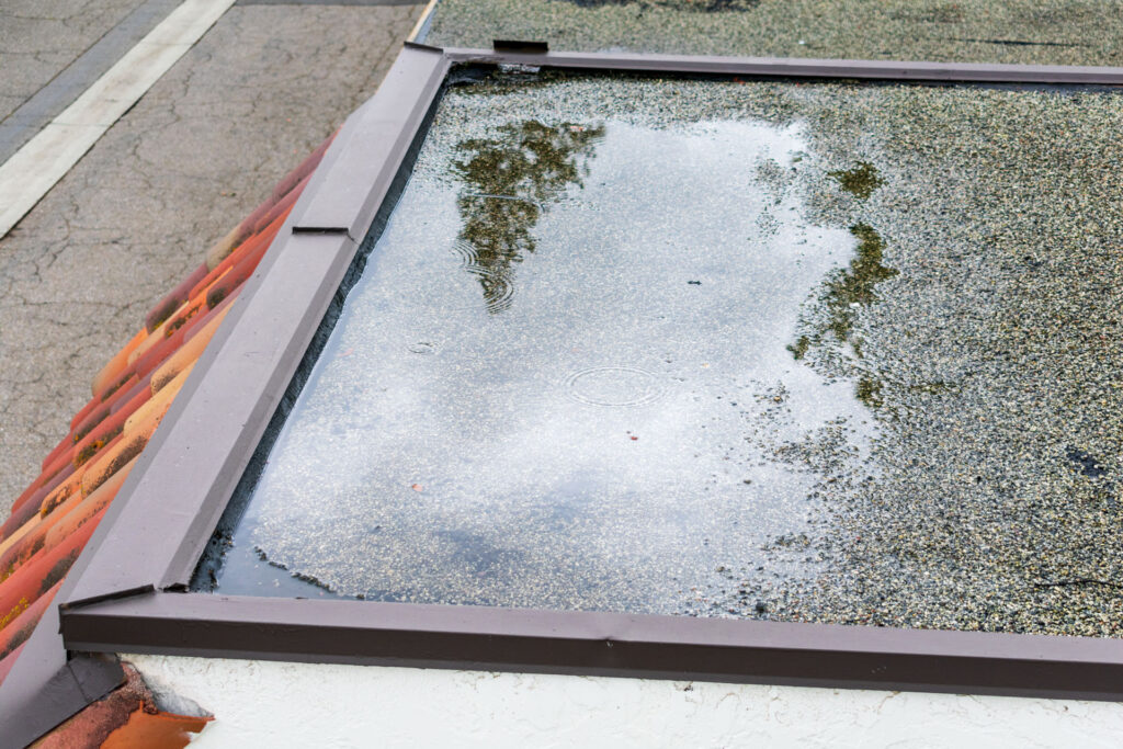 Standing water on a commercial roof caused by drainage issues